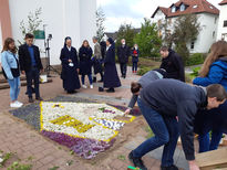 Schönstatt-Jugend legt am Morgen der Primiz einen Blumenteppich in Form des Heiligtums vor das Kirchenportal